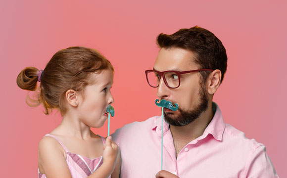 padre e hija poniendo caras con bigotes de papel