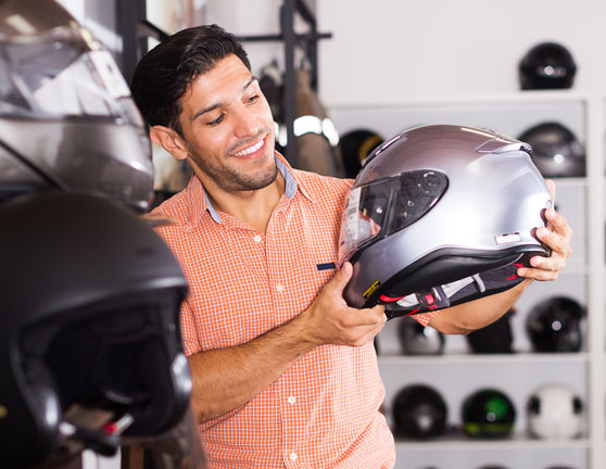 Motociclista sosteniendo un casco en una tienda de equipamiento para motos