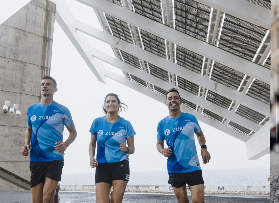 tres personas corriendo en un entorno urbano con camiseta Zurich