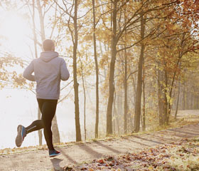 Hombre corriendo por un parque en otoño
